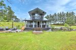 The Jigged Cabin exterior with covered porch, balcony, and grassy waterfront lawn.