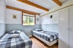 Bright bedroom with two single beds, pine ceiling beams, and large window views.