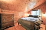 Lakeview Cabin master bedroom with double bed, dresser, and pine paneling.