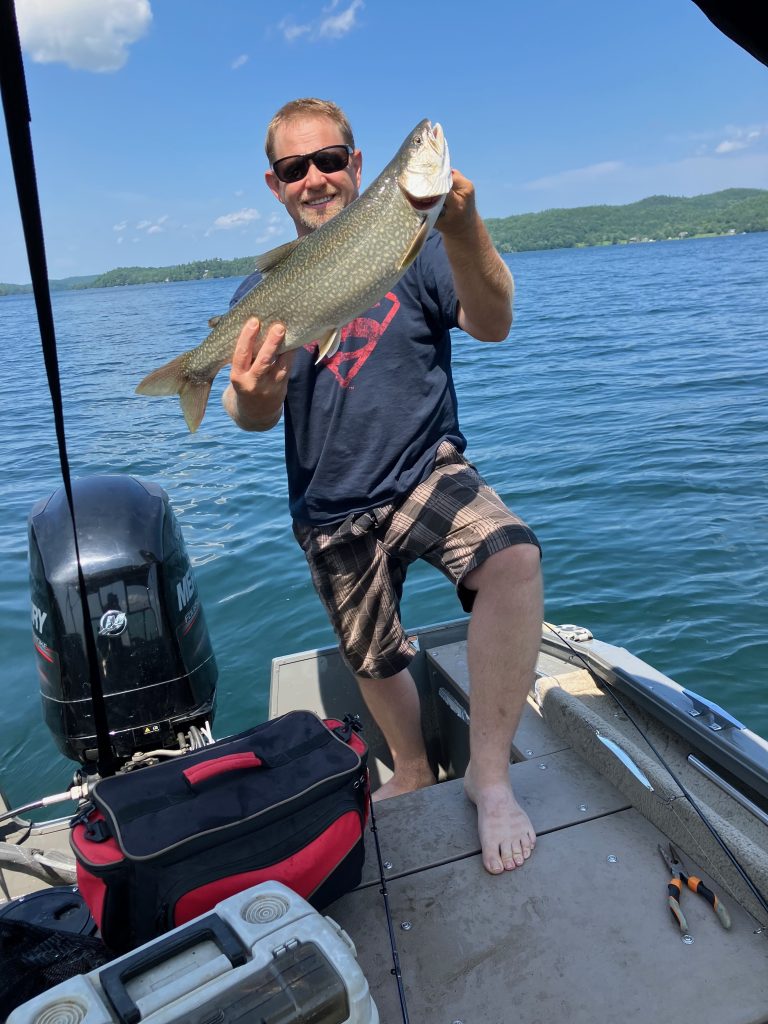 Angler landing a lake trout on a clear summer day at R&B Retreats.