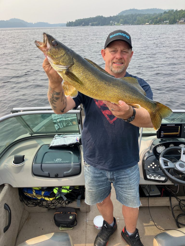 Pêcheur tenant un doré doré de taille trophée attrapé sur le lac Heney lors de vacances de pêche au Québec.