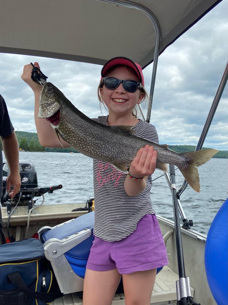 Jeune pêcheur montrant un touladi fraîchement attrapé sur le lac Heney, Québec, près des chalets R&B Retreats